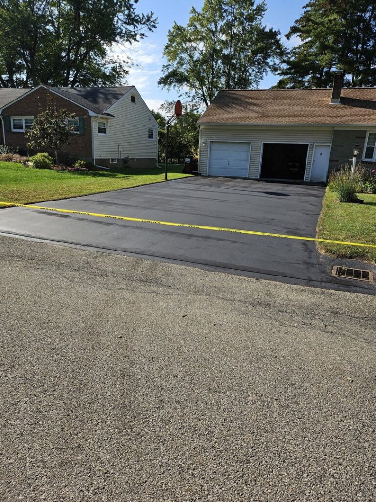 A freshly sealcoated residential driveway with caution tape by Empire Sealcoating in Albany, NY