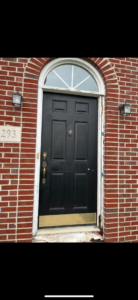 A black front door with a semicircular transom window, showing signs of installation or repair work in progress by JB Recovery in Columbus, OH.