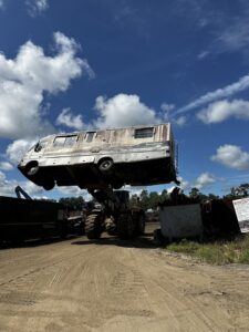 A large front-end loader lifting an old, dilapidated RV for disposal by AAA Rousse Junk Removal Services Inc of Florida in Tampa, FL.