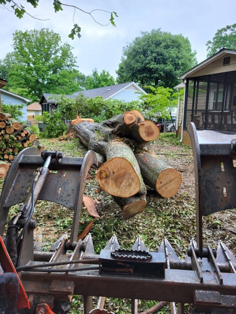 A front-end loader with a grapple attachment moving large tree logs for Morales Services in Greenville, SC.