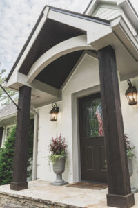 A welcoming front entrance with dark wood pillars and white stucco, painted by Harpeth Painting, LLC. in Nashville, TN.