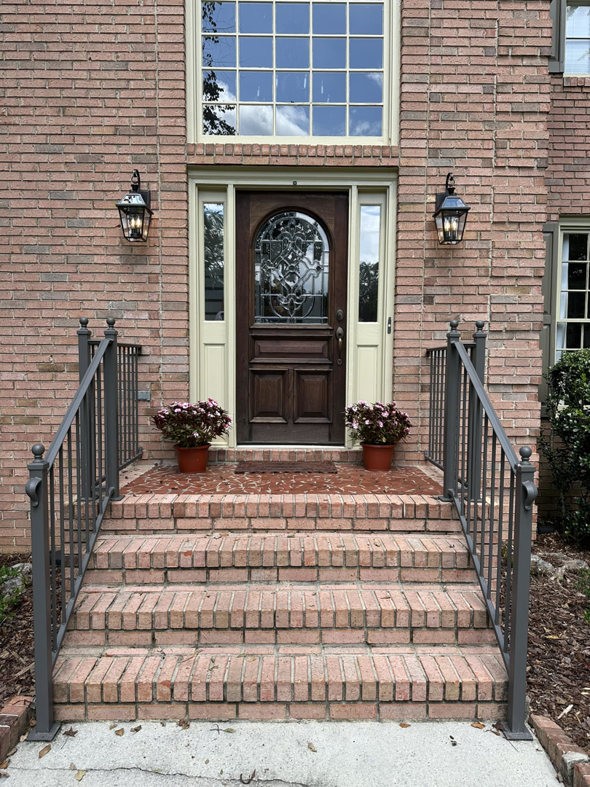A front entrance with newly installed railings and repaired brick steps by Parker Painting Company in Edmond, OK.