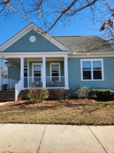 Front exterior house painting with blue siding and white porch columns by Oseguera Painting, LLC in Tallahassee, FL