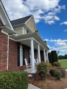 Front exterior view of a traditional brick house with white gutters, showcasing services by Monroe Gutter Pros in Charlotte, NC.