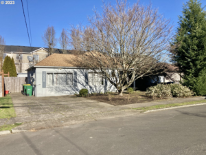 The front exterior of a house with a plain facade and driveway, ideal for curb appeal improvements by Gordon Homes LLC in Portland, OR.
