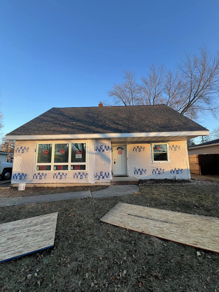 The front exterior of a house under renovation with new windows and house wrap by Sandoval Contracting & Remodeling in Menasha, WI.