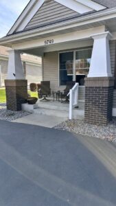 A renovated front porch featuring new white columns and railings, completed by Clear Choice Handyman LLC in Woodbury, MN.