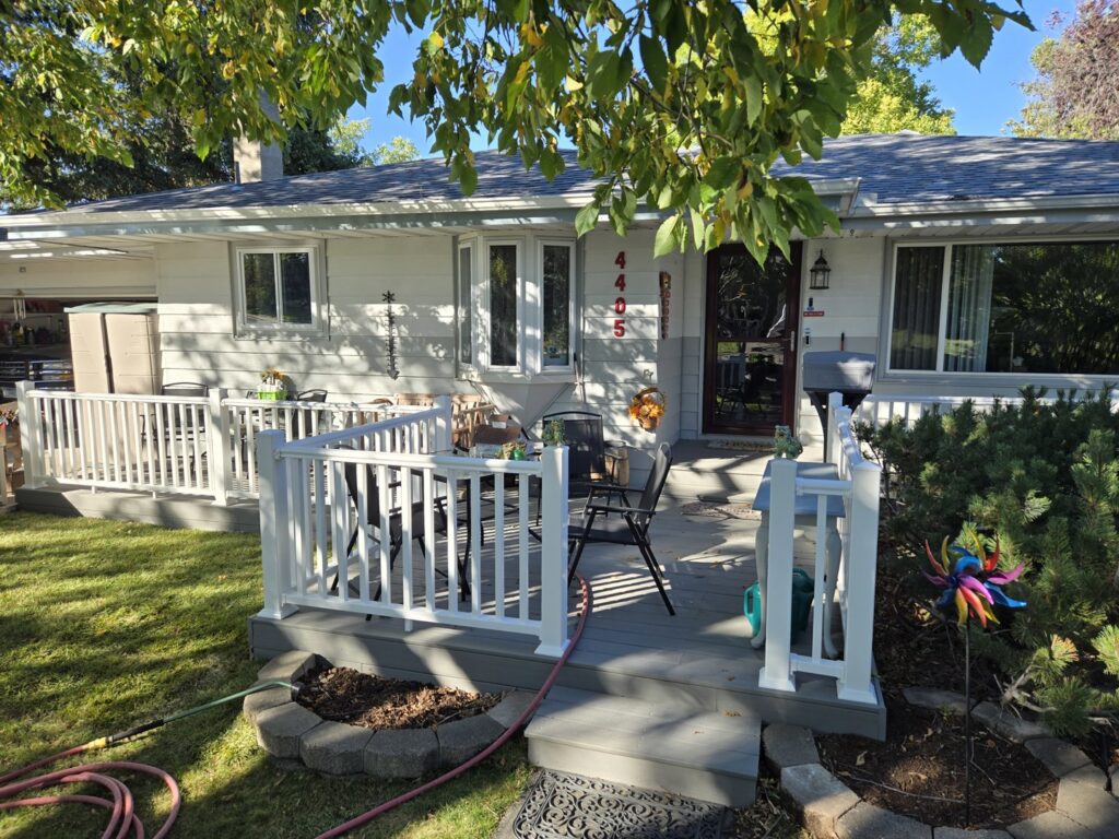 A newly installed front porch deck with crisp white railings, enhancing curb appeal by Great Falls Deck & Carpentry in Great Falls, MT.
