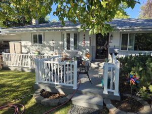 A newly installed front porch deck with crisp white railings, enhancing curb appeal by Great Falls Deck & Carpentry in Great Falls, MT.