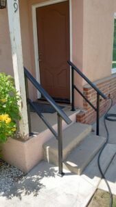 Front porch with newly installed black metal handrails by Cal Heights Construction And Handyman Services in Bakersfield, CA