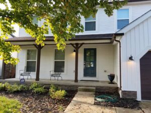 A front porch with newly installed white siding and a blue front door by The Window Man of Ohio in Westerville, OH.