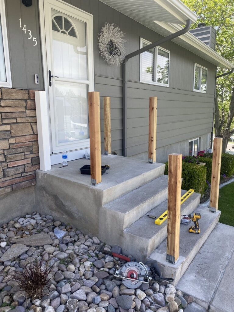 Installation of new wooden railing posts on front porch steps, with tools visible, by No Delay SVCS in Pocatello, ID.