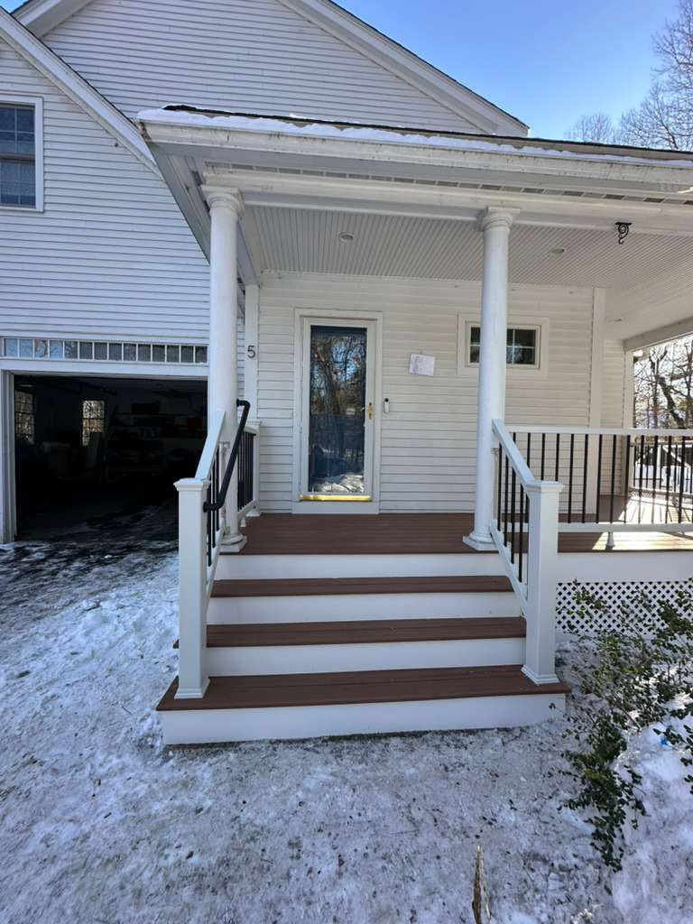 The front entrance of a home with newly installed porch steps and a deck, showcasing handyman services from Remodel or Renew Home Improvement in Worcester, MA.