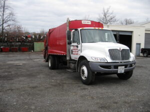 Front view of a red and white garbage truck, branded B & B Refuse Inc, for waste collection in Rockville, MD.