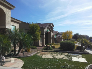 A residential front yard with tree debris on artificial turf, indicating cleanup after tree services by Arts Aspect Tree Services in Mesa, AZ