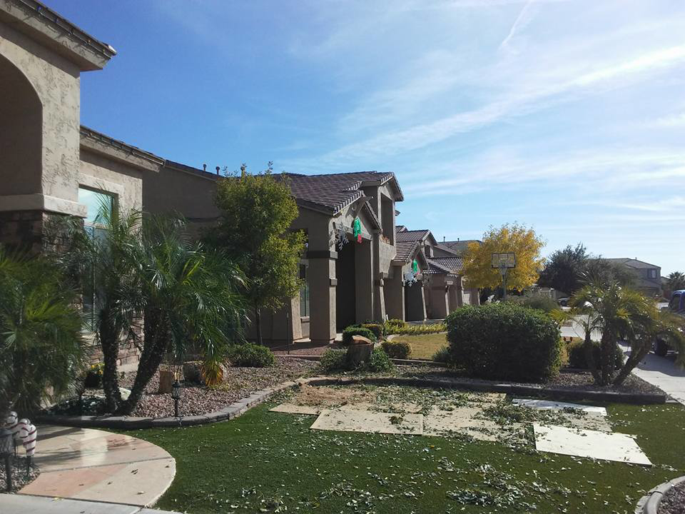 A residential front yard with tree debris on artificial turf, indicating cleanup after tree services by Arts Aspect Tree Services in Mesa, AZ