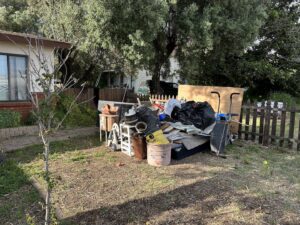A large pile of mixed junk and debris in a front yard, ready for removal by Eastlake Hauling and Junk Removal, LLC in Chula Vista, CA.