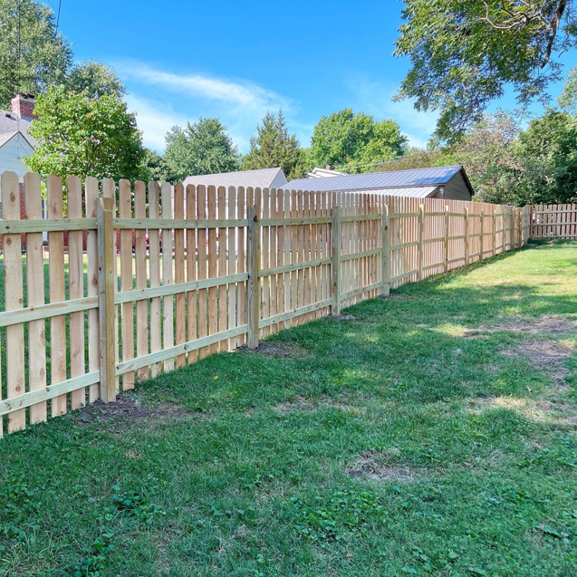 A long, newly installed wooden picket fence enclosing a backyard by Cutting Edge Contracting and Handyman in Minneapolis, MN.