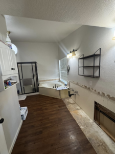 A full view of a bathroom renovation project with a tub, shower, and wall demolition by CK Customs LLC in Surprise, AZ.