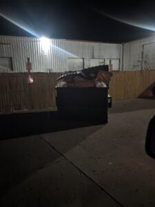 A full dumpster with junk at night, representing waste collection by CARDS - City of Springdale in Springdale, AR