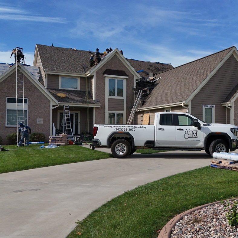 Full house roof replacement project with workers and company truck by A&M Contractors LLC in Waukesha, WI