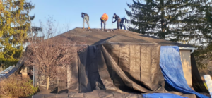 A full house roof replacement project underway by Manny's Sb Construction Inc, with protective tarps in Goshen, NY.