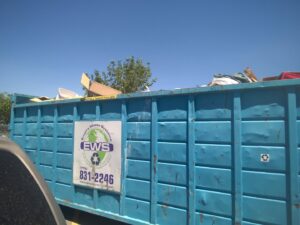 A blue roll-off dumpster from Empire Waste Systems in Carson City, NV, filled with various items for junk removal