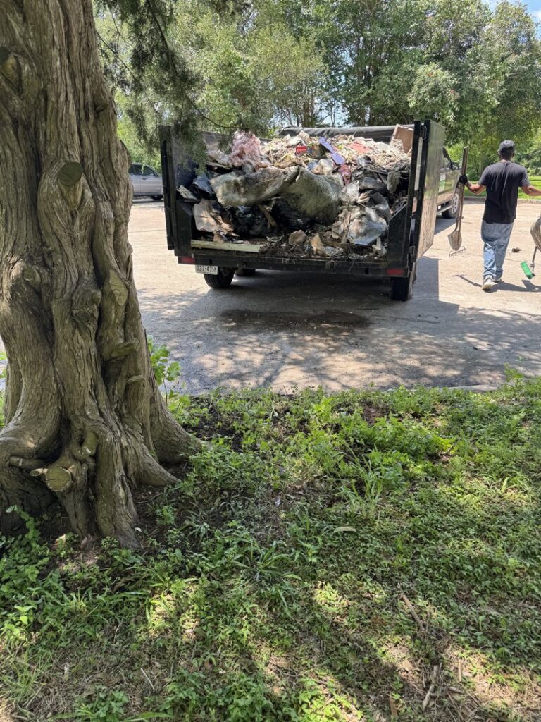 A full junk removal trailer with a worker standing nearby, showcasing a completed job by Clear Your Junk - Pearland, Houston, TX.