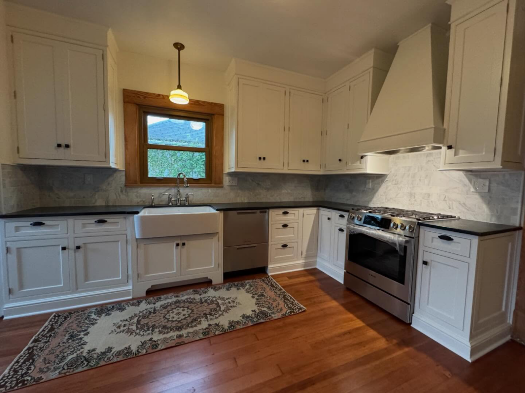 A complete kitchen remodel featuring white cabinets and dark countertops by Balance Painting & Remodeling, LLC in Portland, OR.