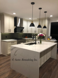 A complete kitchen remodel featuring white cabinets, a large island, and modern pendant lights by Surtec Remodeling Inc. in Pittsburgh, PA.