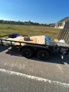 A wide shot of a utility trailer filled with construction waste and debris, ready for hauling by Resilient Trash and Cleaning LLC in New Orleans, LA.