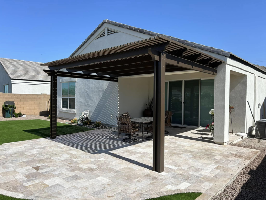 A full view of a completed brown pergola and paved patio attached to a house by Az Sun Covers in Glendale, AZ.