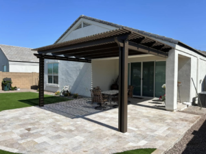 A full view of a completed brown pergola and paved patio attached to a house by Az Sun Covers in Glendale, AZ.