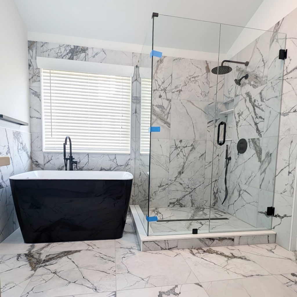 A complete view of a modern remodeled bathroom with a freestanding tub and glass shower enclosure by Ensotile - Atlanta Bathroom Remodeling in Stone Mountain, GA
