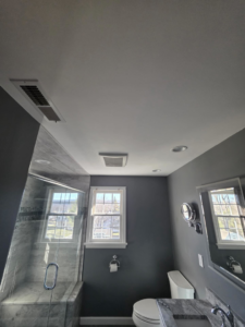 A fully renovated modern bathroom with dark gray walls, new vanity, toilet, and glass shower by Precision Property Services LLC in South Windsor, CT.