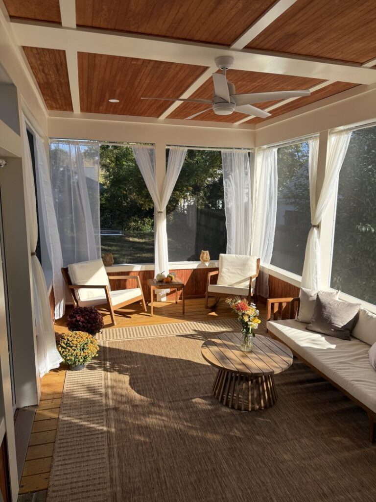 A beautifully furnished screened porch with a ceiling fan, showcasing handyman work by Elite Xteriors NC in Cary, NC.