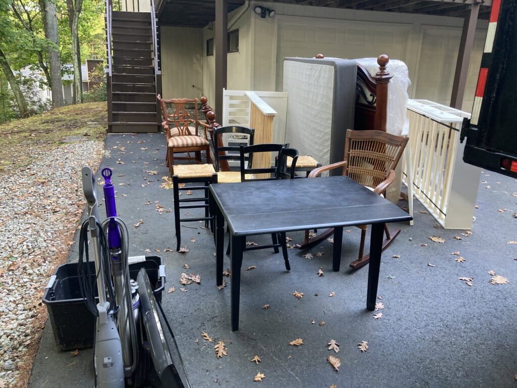 Various furniture items, including chairs, a table, a mattress, and a crib, placed outside for pickup by Rizzo Junk Removal in Nashua, NH.