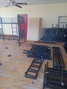 Metal bunk bed frames and wood panels being removed from a room by Cox Junk & Debris Removal in Buffalo, NY.