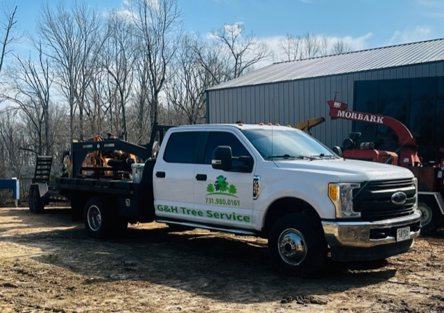 G&H Tree Service branded truck with tree removal equipment and a Morbark chipper in Jackson, TN.