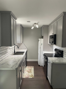 Full view of a completed galley kitchen remodel featuring grey cabinets and new appliances by Wareham Home Improvements in Frederick, MD.