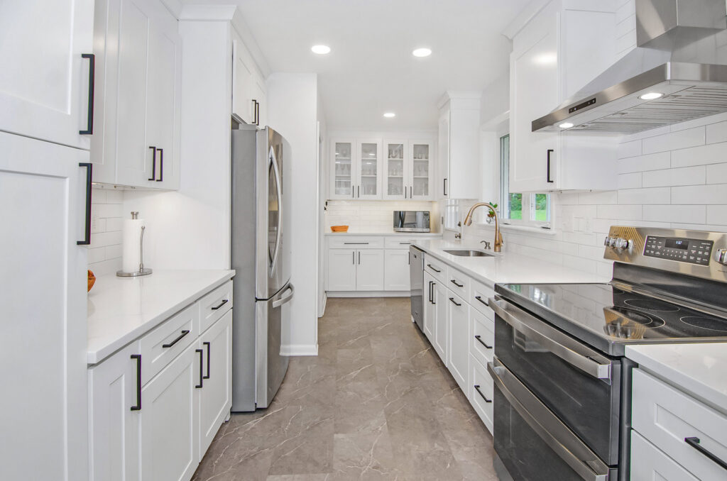 A galley kitchen remodel featuring white cabinets, stainless steel appliances, and grey floor tiles by Total Craftsmen in Towson, MD