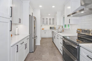 A galley kitchen remodel featuring white cabinets, stainless steel appliances, and grey floor tiles by Total Craftsmen in Towson, MD