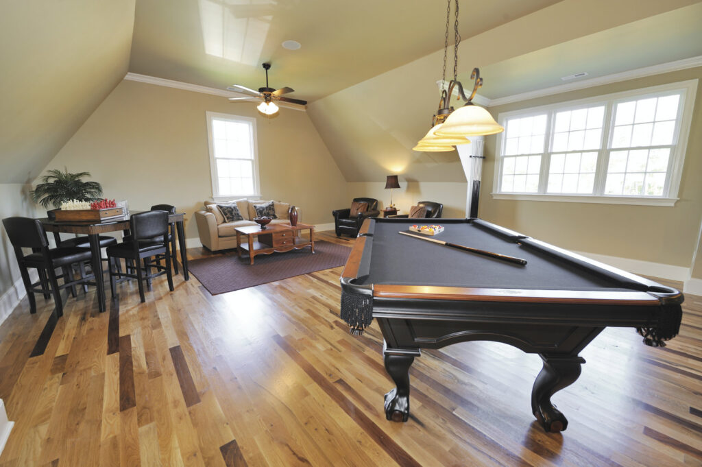 A spacious game room featuring a pool table, seating area, and ceiling fans, completed by Paradise Found Construction in Cary, NC.