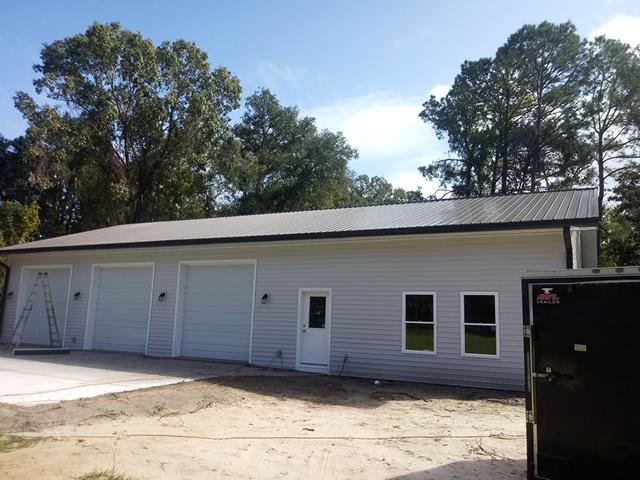 A large garage or workshop building under construction or renovation with ladders visible by Charleston Exteriors in Charleston, SC.
