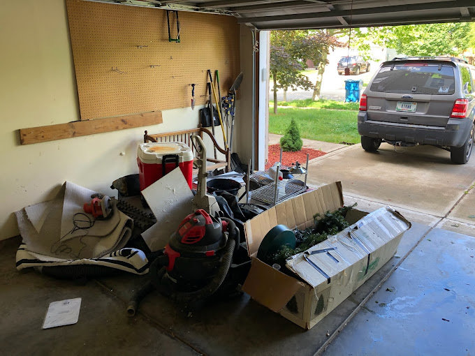 A garage filled with various items and clutter, demonstrating a junk removal and cleanout service by Indy Trash Guy in Fishers, IN.