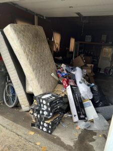 A cluttered garage with old mattresses, boxes, and various debris piled up for junk removal by Missoula Junk Removal, LLC in Missoula, MT.