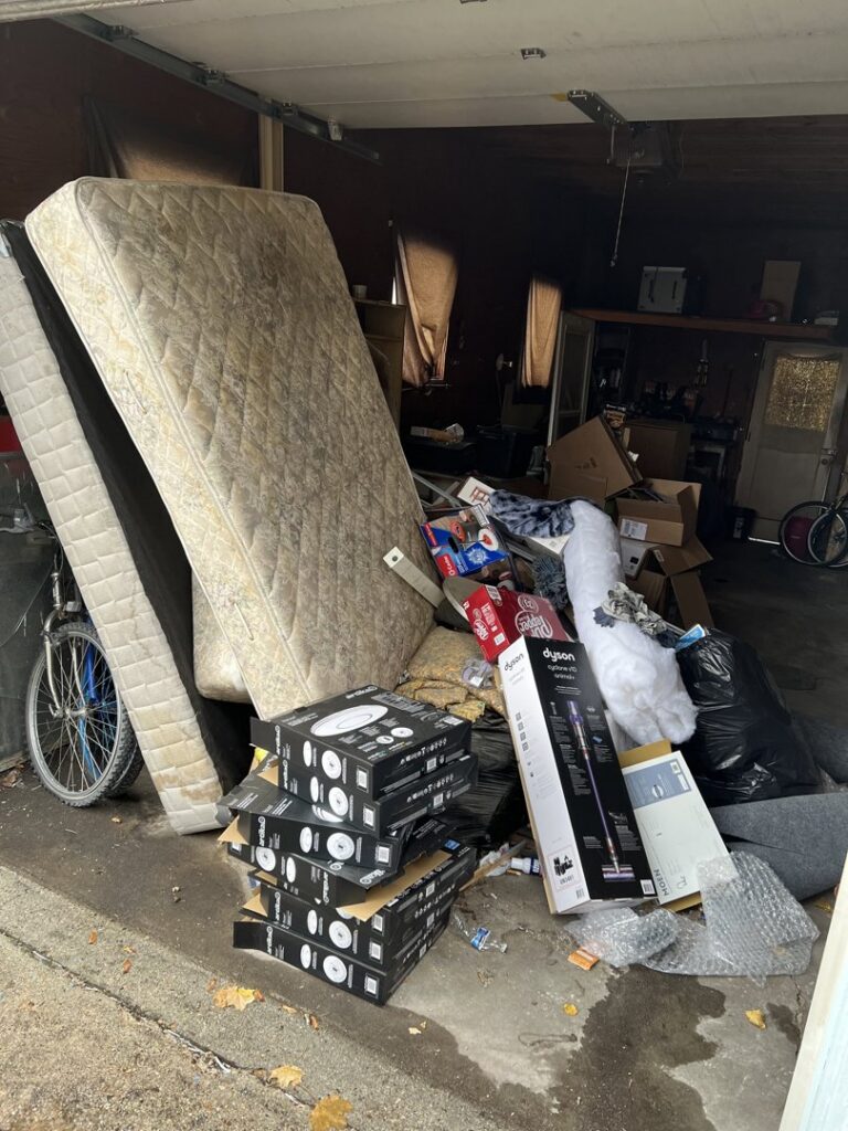 A cluttered garage with old mattresses, boxes, and various debris piled up for junk removal by Missoula Junk Removal, LLC in Missoula, MT.
