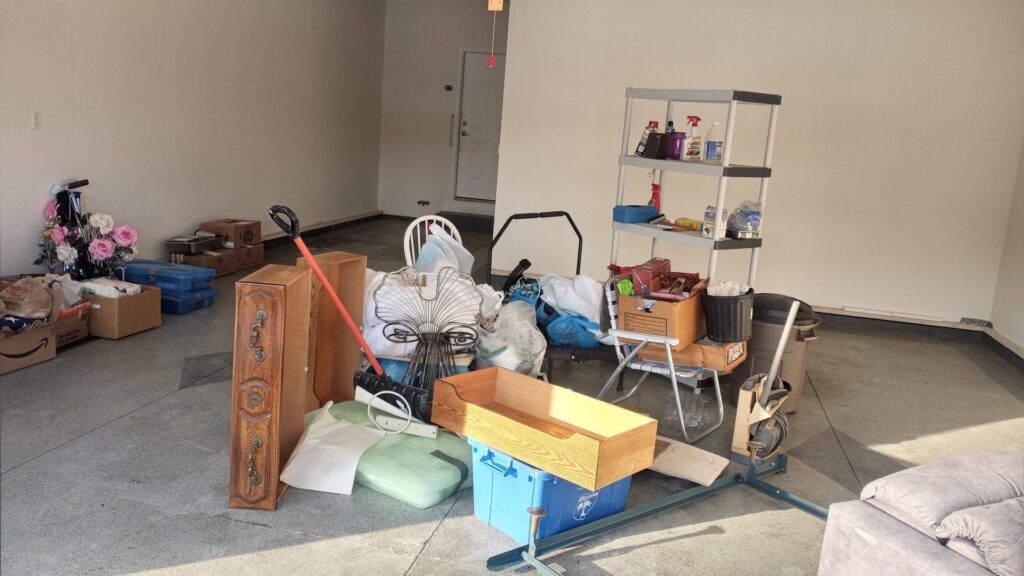 A garage with various household clutter and furniture pieces, indicating items ready for removal by HAULA Junk Removal in Canton, OH.