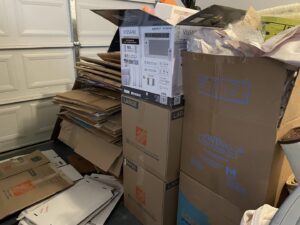A garage corner with stacked cardboard boxes and an old air conditioner unit, ready for JunkStart junk removal in San Antonio, TX.
