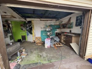 An interior view of a garage undergoing demolition or cleanout, showing debris and exposed walls, by Richie Bros Junk Removal in Urbandale, IA.